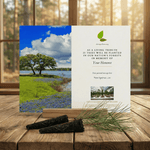 Memorial tree planting card with scenic image and text on a wooden surface.
