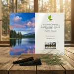 Pet memorial card with a scenic lake and forest design on a wooden surface.