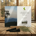 Memorial card with mountain view and tree planting information on a wooden surface.