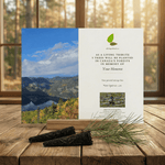 Memorial card with scenic view and tree planting information on a wooden surface.
