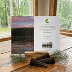Memorial tree planting card with scenic images on a wooden surface