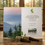 Card with scenic view of mountains and trees, featuring a message about planting trees, on a wooden surface with a window in the background.