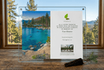 Lucite memorial tree plaque with nature scene and text on a wooden surface with window view