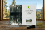 Acrylic plaque with nature-themed design on a wooden surface with a window view of trees.