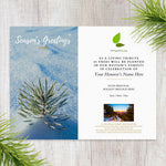 Holiday card with snowy pine branch and personalized space on a wooden surface.