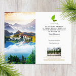 Thank you greeting card with mountain landscape and tree planting message on a wooden surface.