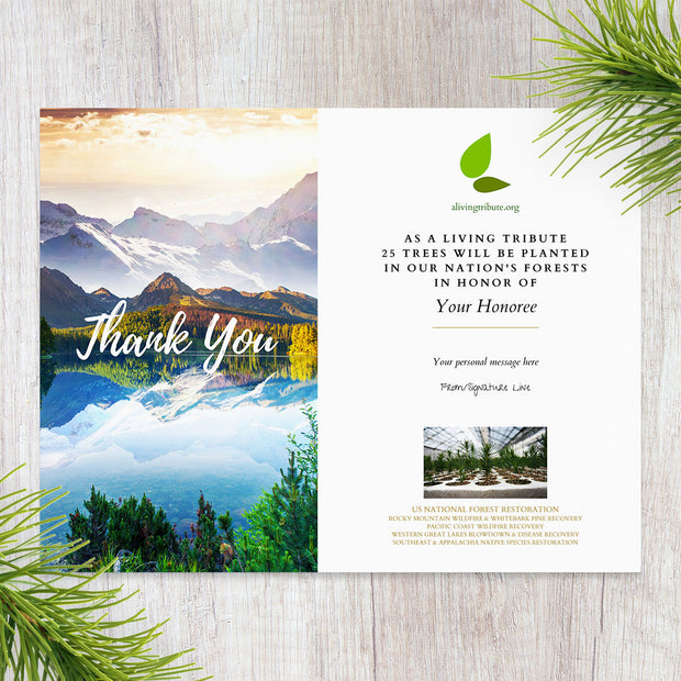 Thank you greeting card with mountain landscape and tree planting message on a wooden surface.